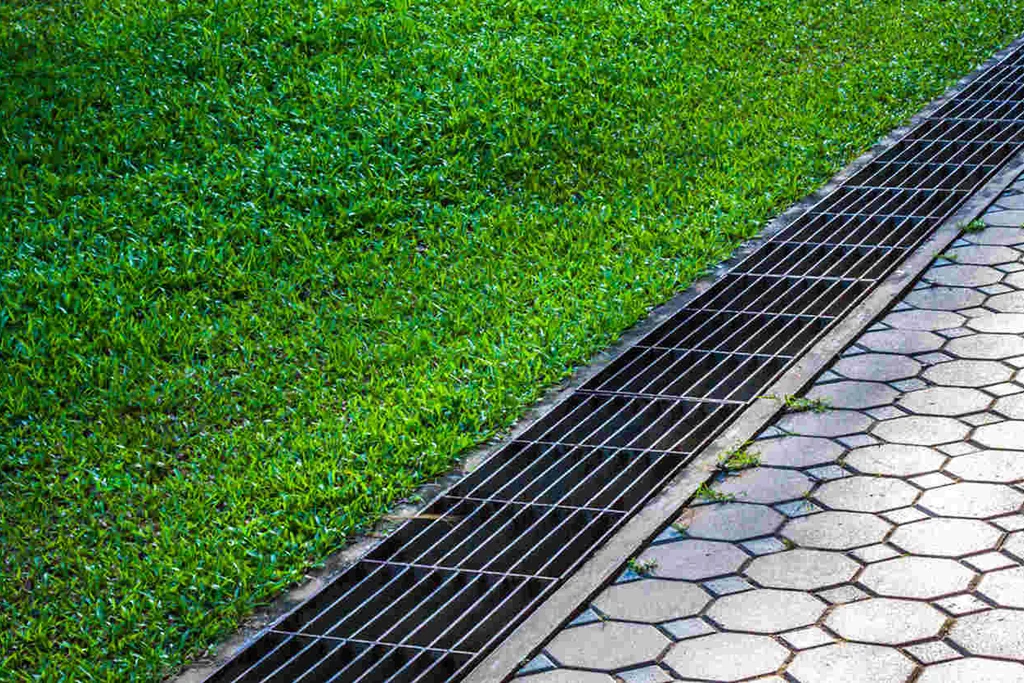 Surface water drainage channel between lawn and driveway.